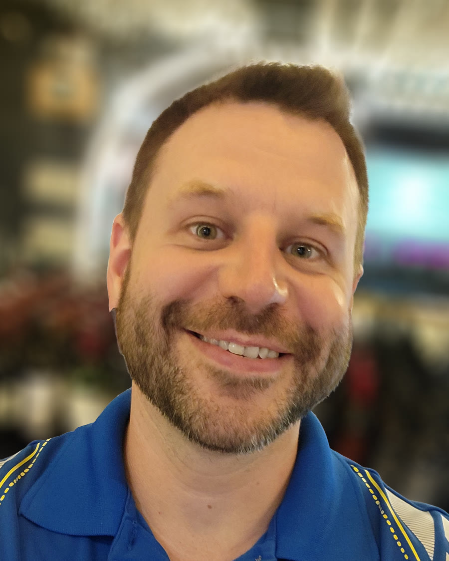 Portrait of Brad Thomison, smiling, in a blue polo shirt